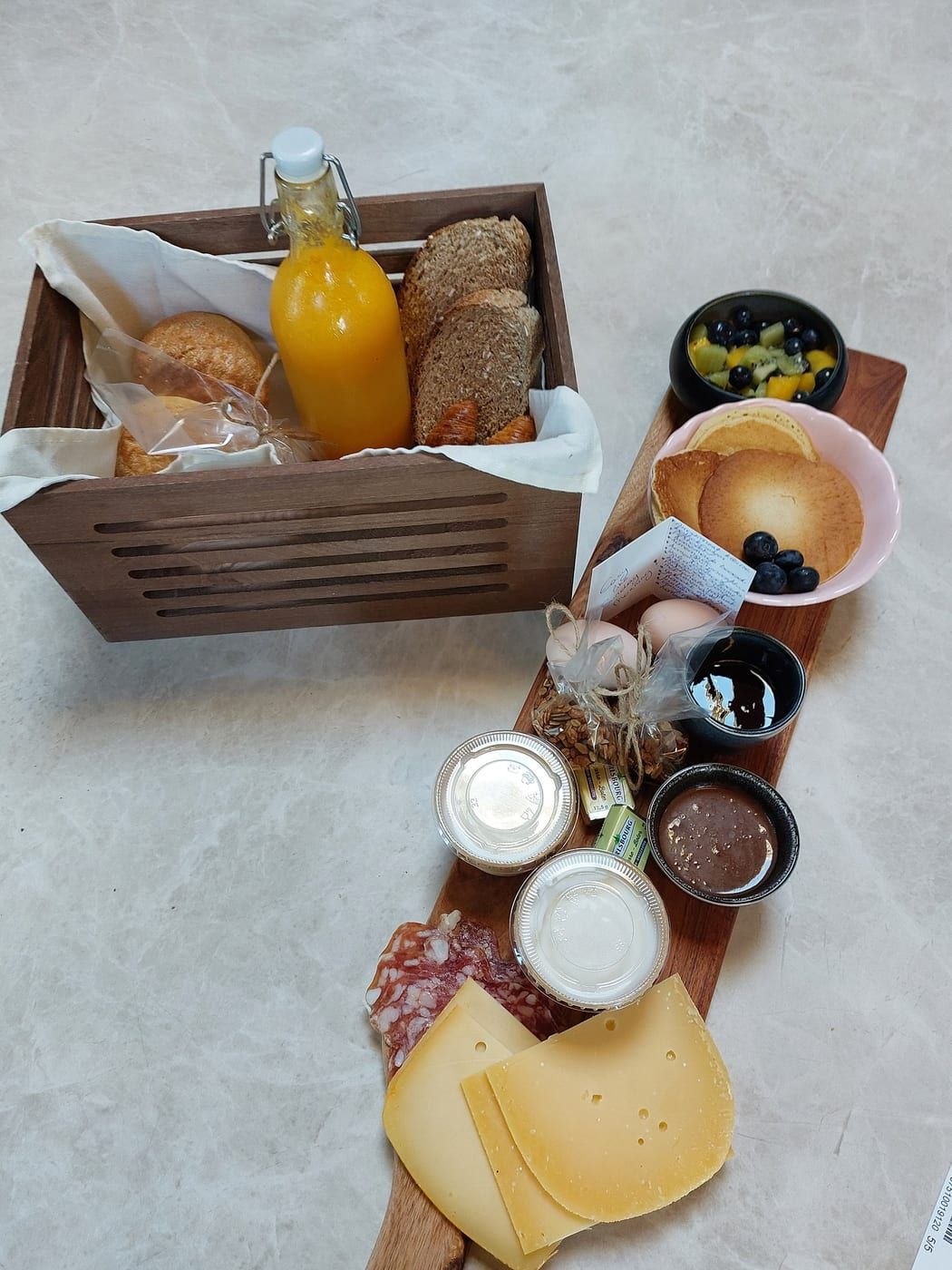 Ontbijtmand met brood, koffiekoeken, yoghurt met granola en vers fruit
